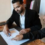 Two professionals discussing a business graph at an office desk.