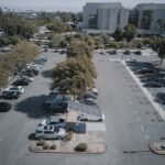 High-angle view of a parking lot with solar panels and parked vehicles, surrounded by greenery.