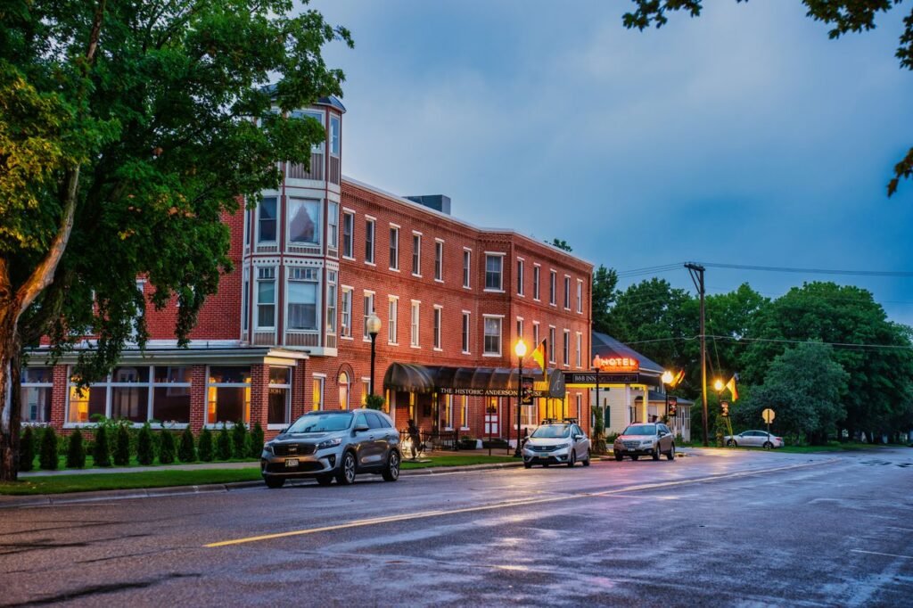 Highway Hotel A vibrant view of a historic hotel at dusk in Wabasha, MN, with parked cars and streetlights.