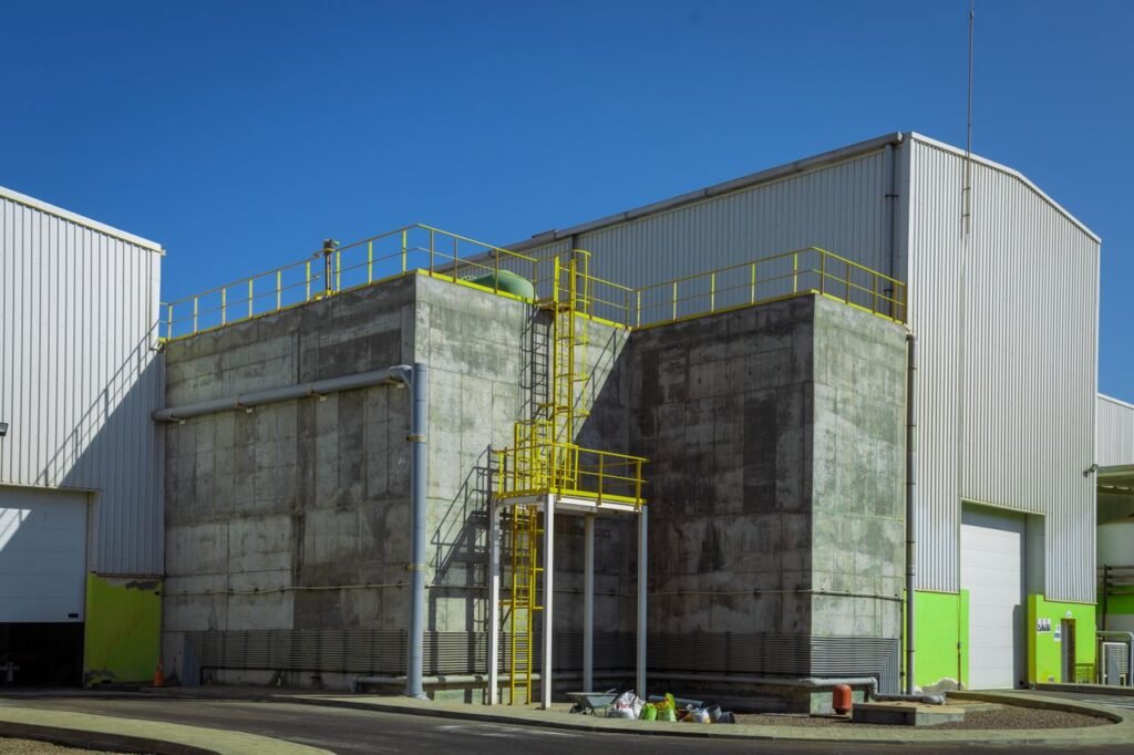 pexels-photo-17180396-17180396 Modern industrial warehouse exterior with concrete facade and yellow railings under clear blue sky.