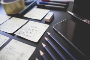 Planned for success A creative workspace featuring UI design plans, pencils, a smartphone, and other office tools.