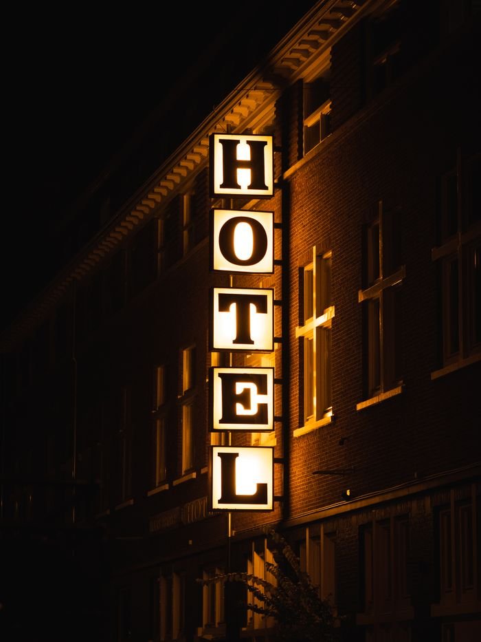Hotels A bright hotel sign glowing on a building facade during nighttime.