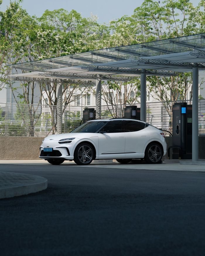 Profitable EV charging A white electric SUV charging at an outdoor station under clear blue skies.