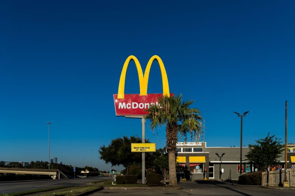 Highway Food Court McDonald's golden arches sign with palm tree in front of a clear blue sky