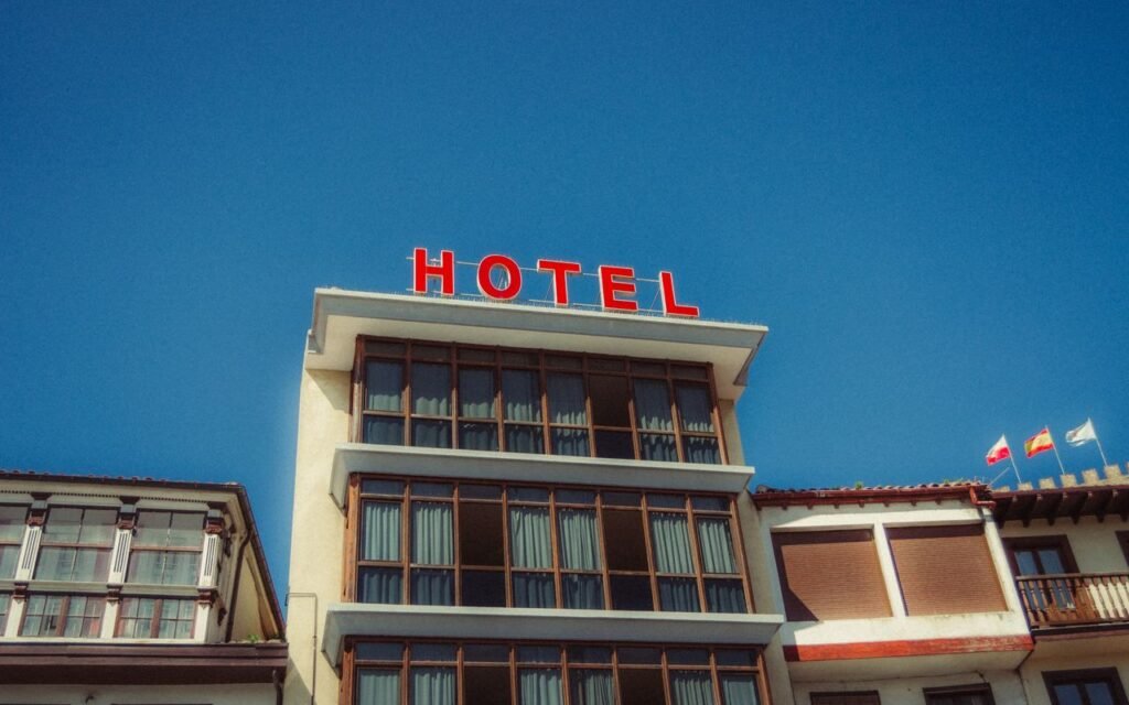 pexels-photo-35479245-35479245 Colorful hotel facade in Asturias, Spain with bright signage against a clear sky.