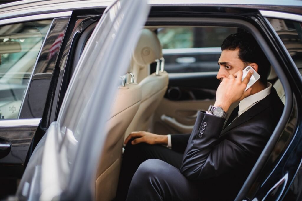 Corporate EV Vehicles Professional man in suit making a phone call while sitting in a vehicle.