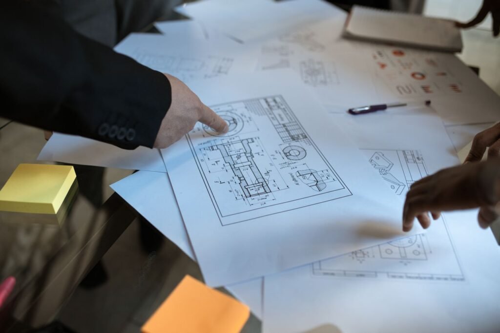 pexels-photo-5922202-5922202 Engineers discussing blueprints at a workspace, focusing on teamwork and architecture design.